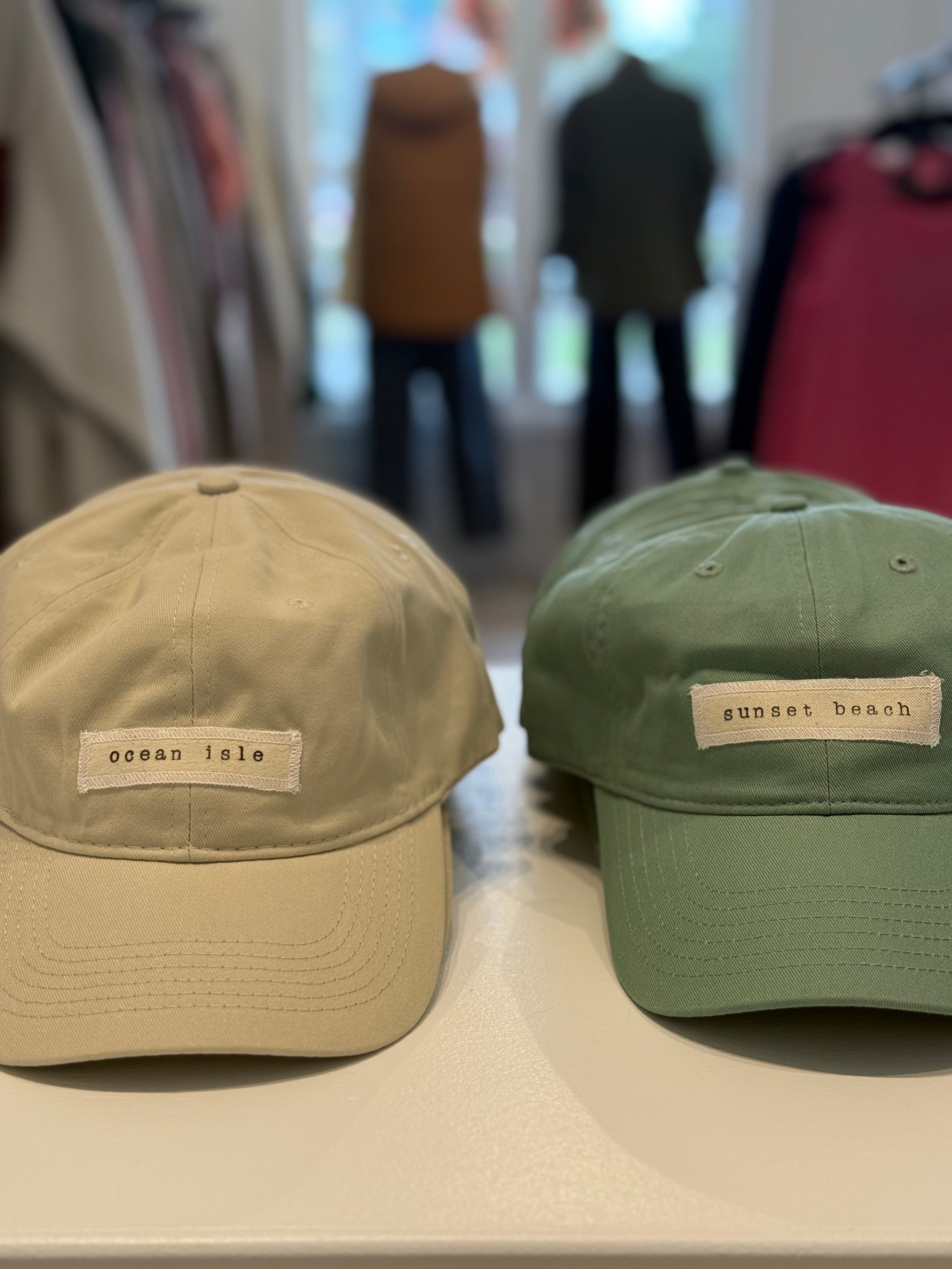 Two baseball caps, one beige and one green, with text labels on a blurred background.