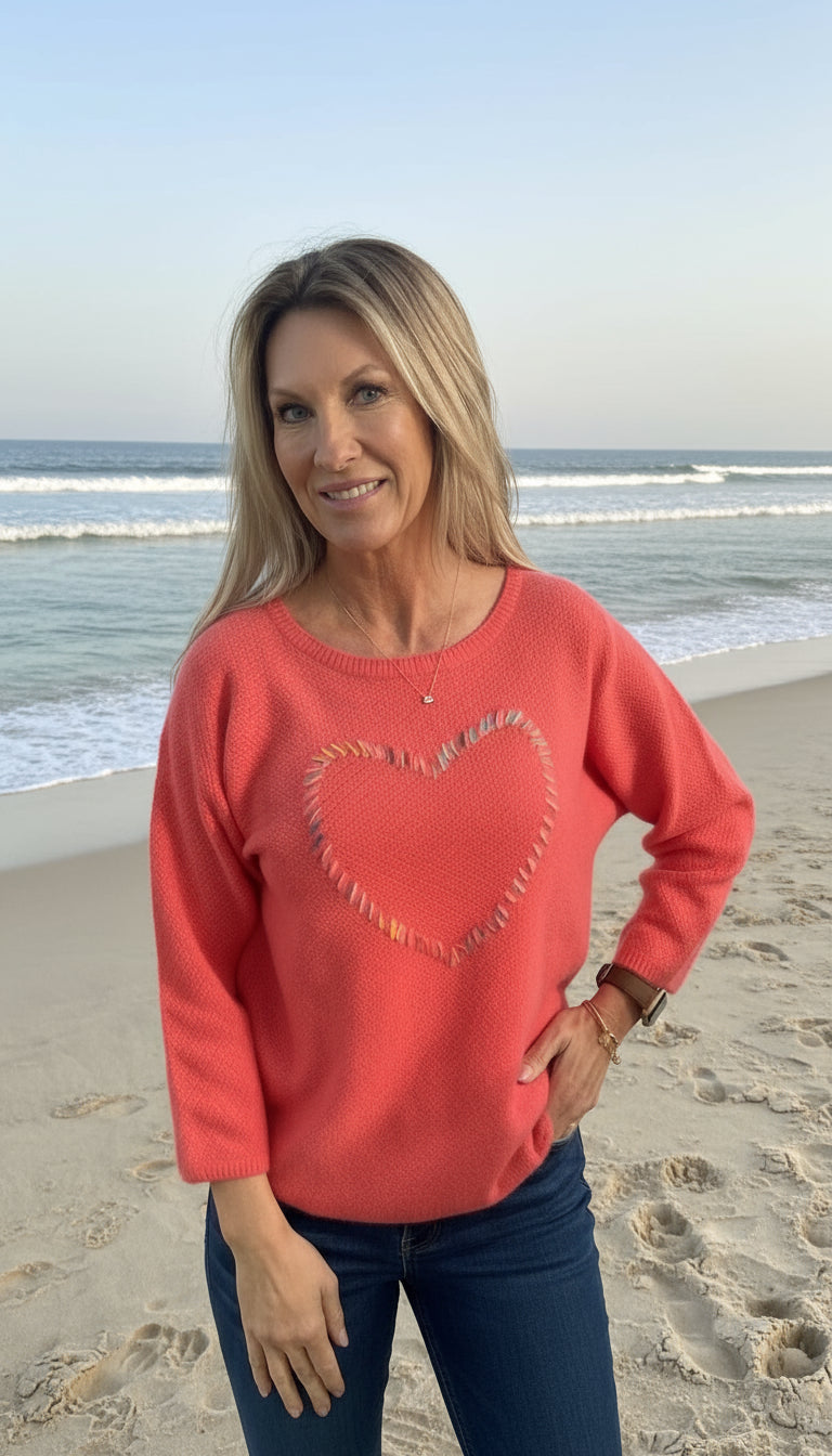 Woman wearing a red sweater with a colorful heart design on a white background