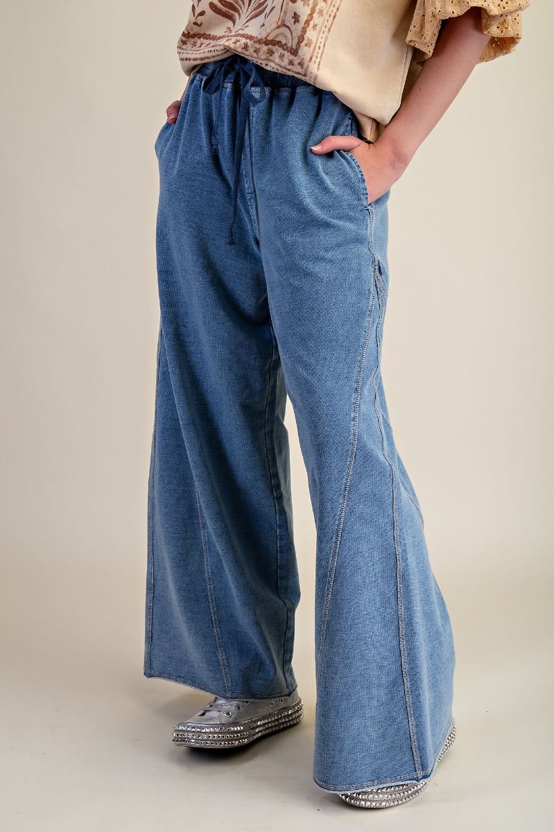 Person wearing blue wide-leg jeans on a plain background