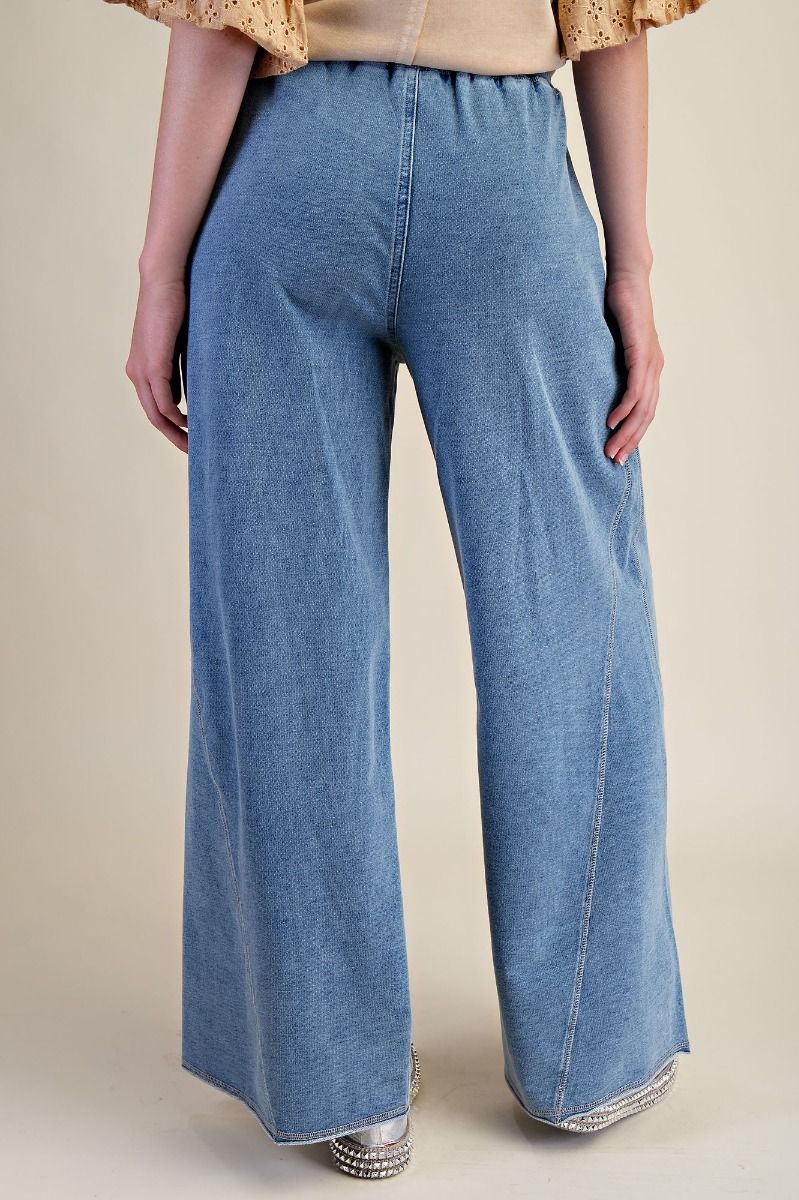 Blue denim wide-leg pants worn by a person on a beige background