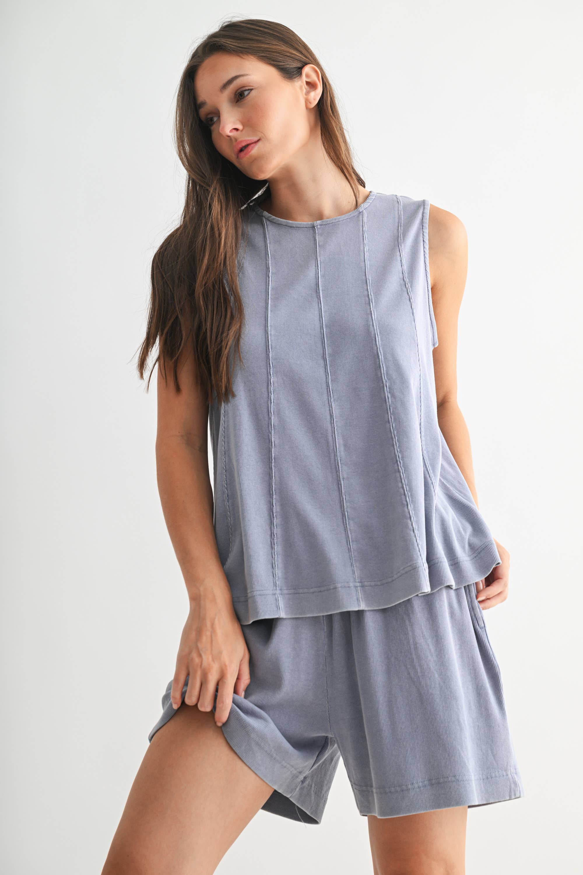 Woman wearing a light blue sleeveless top and shorts set on a white background