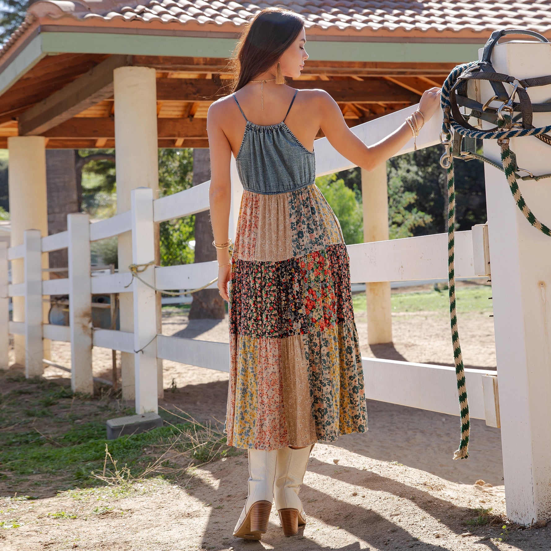 Woman in a floral dress standing next to a horse in an outdoor setting