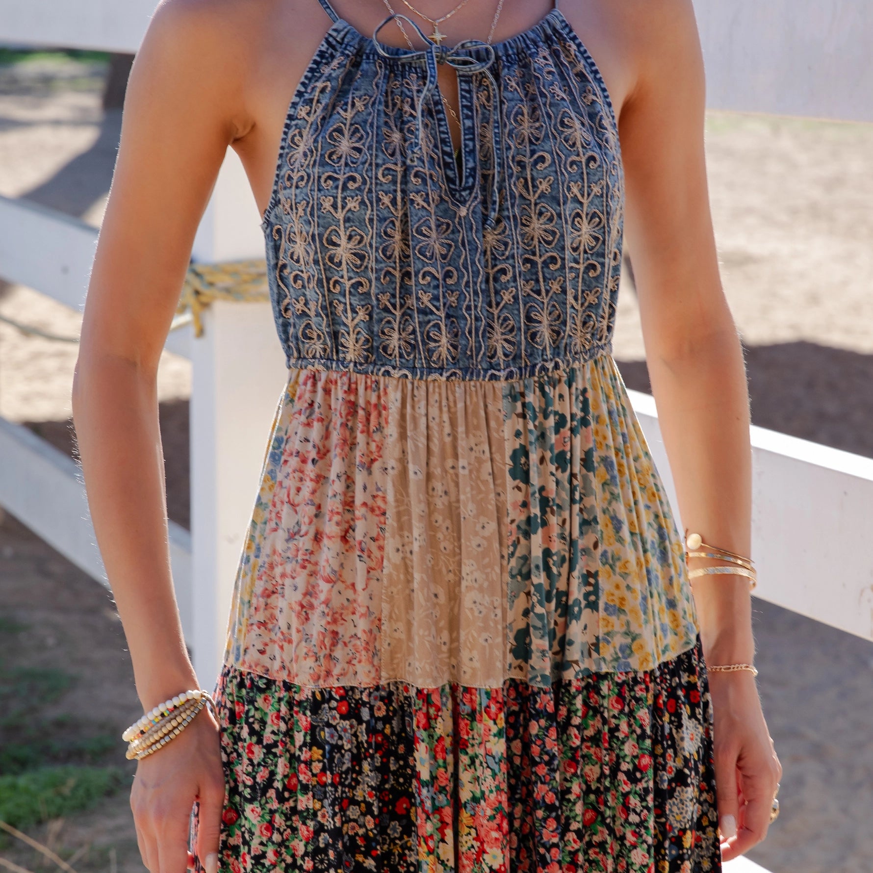 Woman wearing a layered dress with floral patterns outdoors.