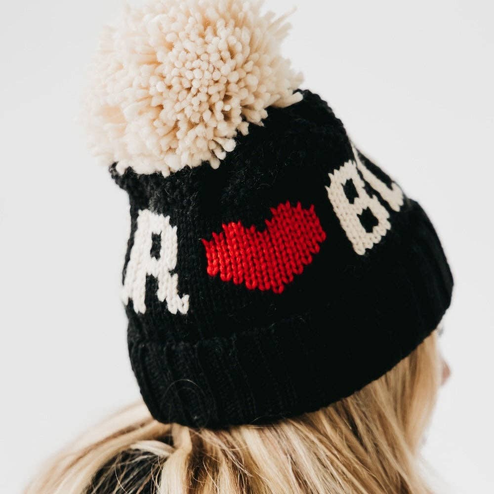 Black knit beanie with a red heart and white text on a white background