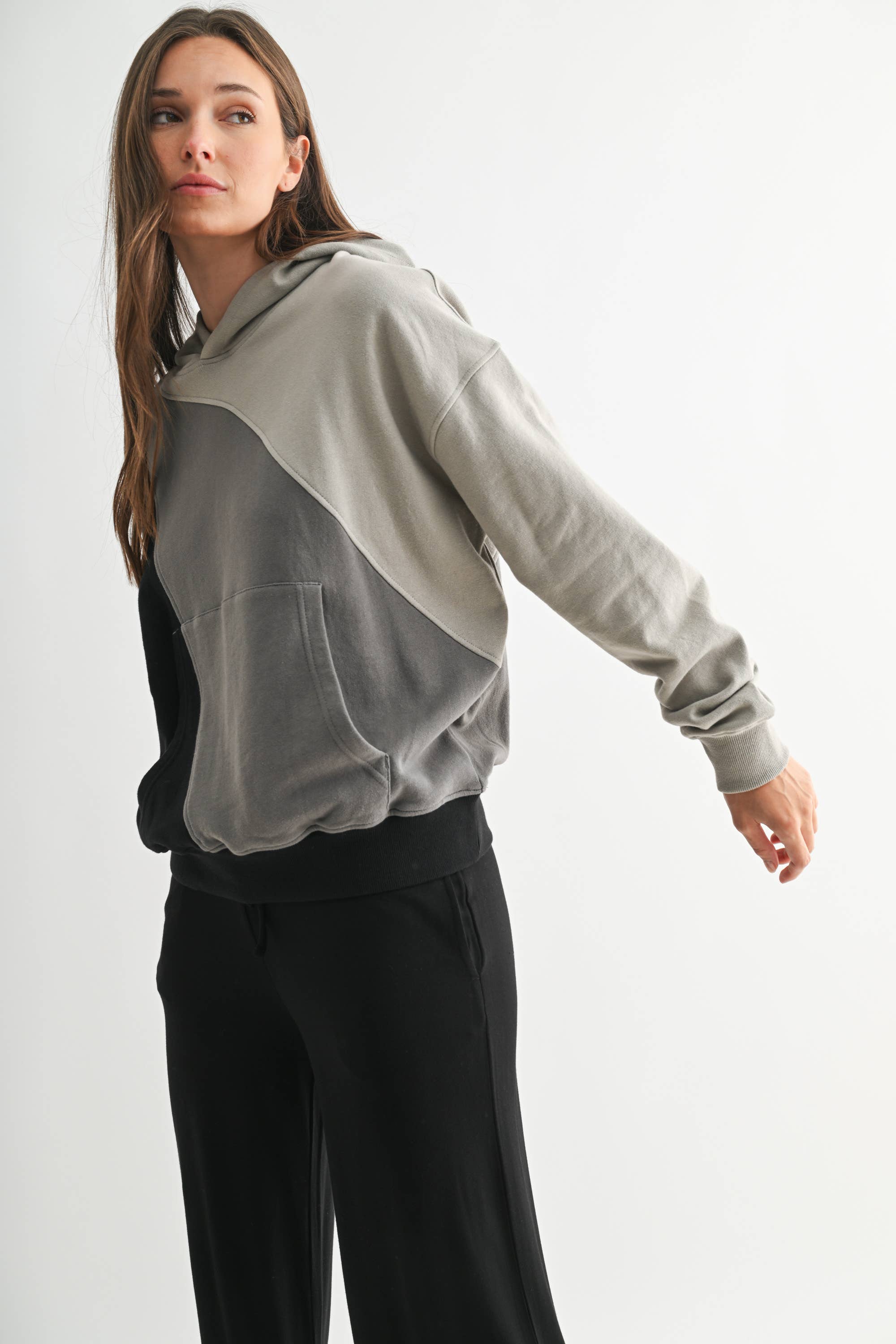 Woman wearing a two-tone hoodie and black pants on a white background