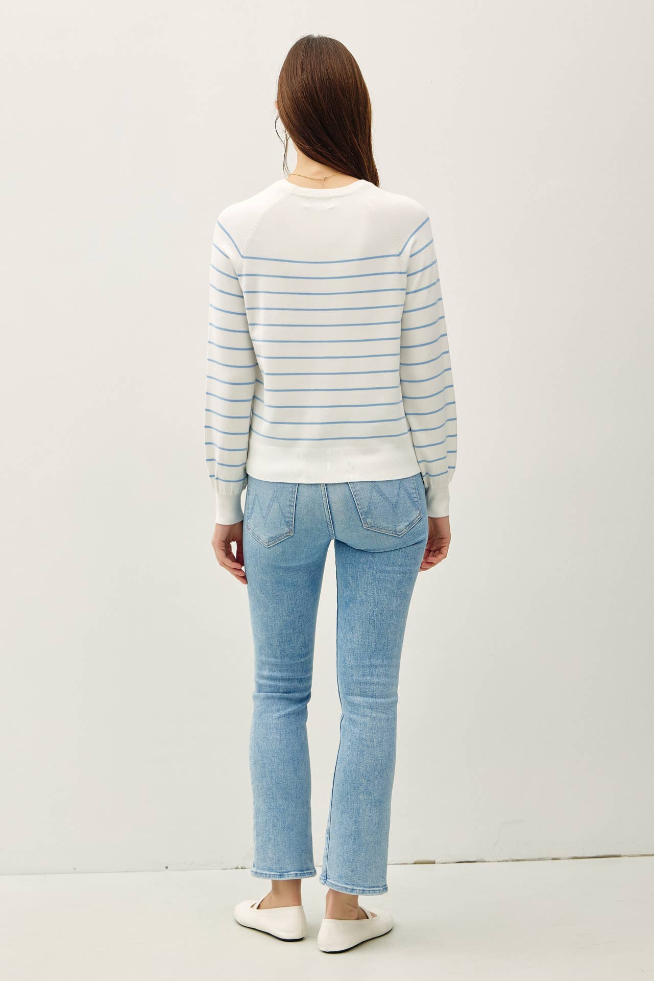 Person wearing a striped sweater and light blue jeans on a white background