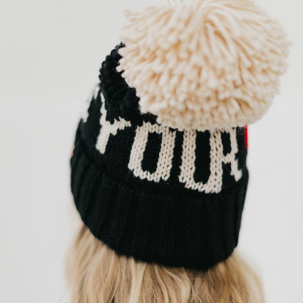 Black knit beanie with a beige pom-pom on a white background