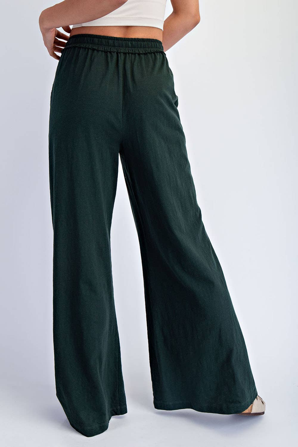 Dark green wide-leg pants worn by a person on a white background