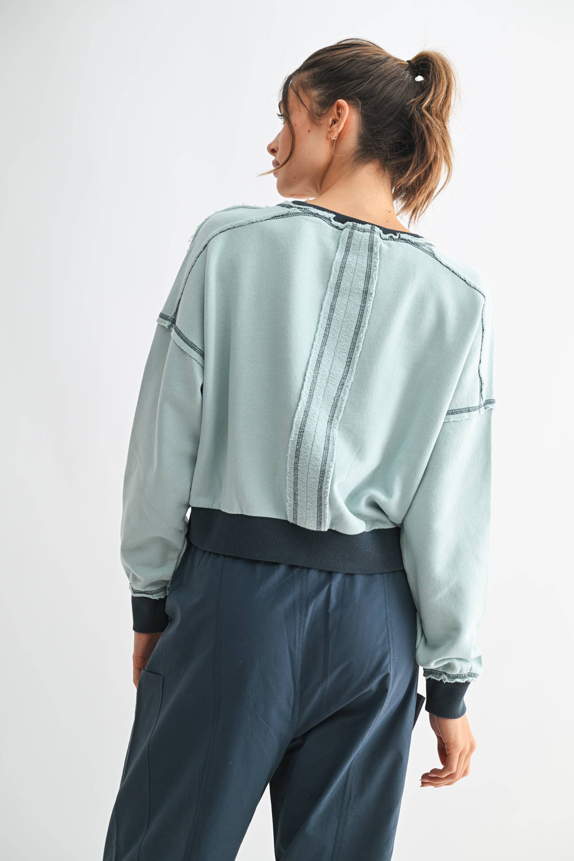 Person wearing a light blue jacket and dark pants on a white background