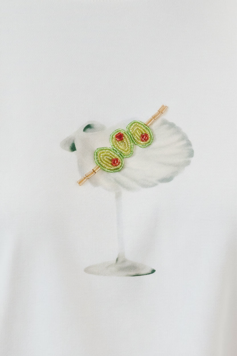 Margarita glass with a skewer of avocado slices and cherry tomatoes on a white background