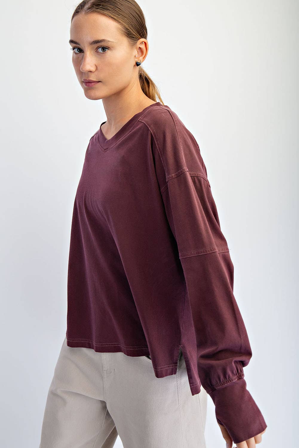 Woman wearing a burgundy oversized sweatshirt against a white background