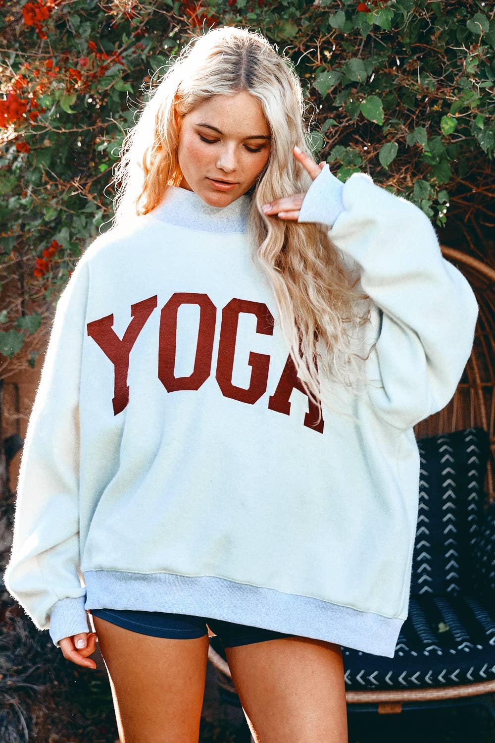 Person wearing a white sweatshirt with 'YOGA' printed in red letters outdoors.