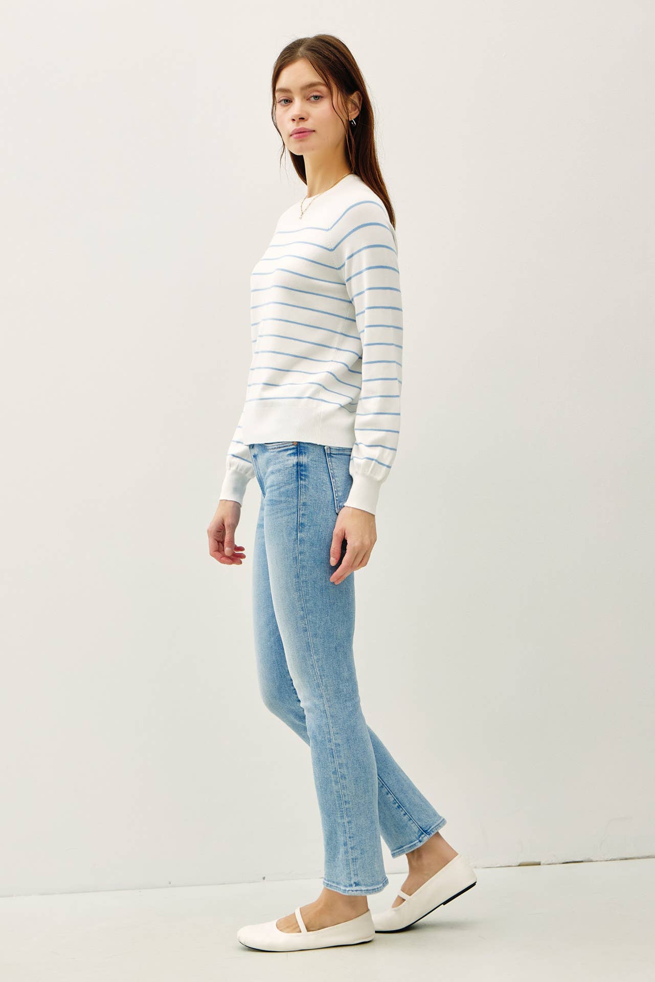 Woman wearing a striped sweater and light blue jeans on a white background