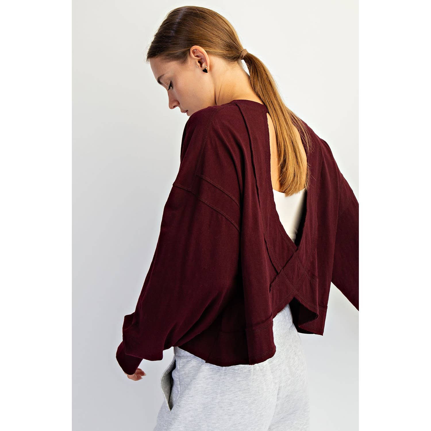 Woman wearing a burgundy open-back top on a white background