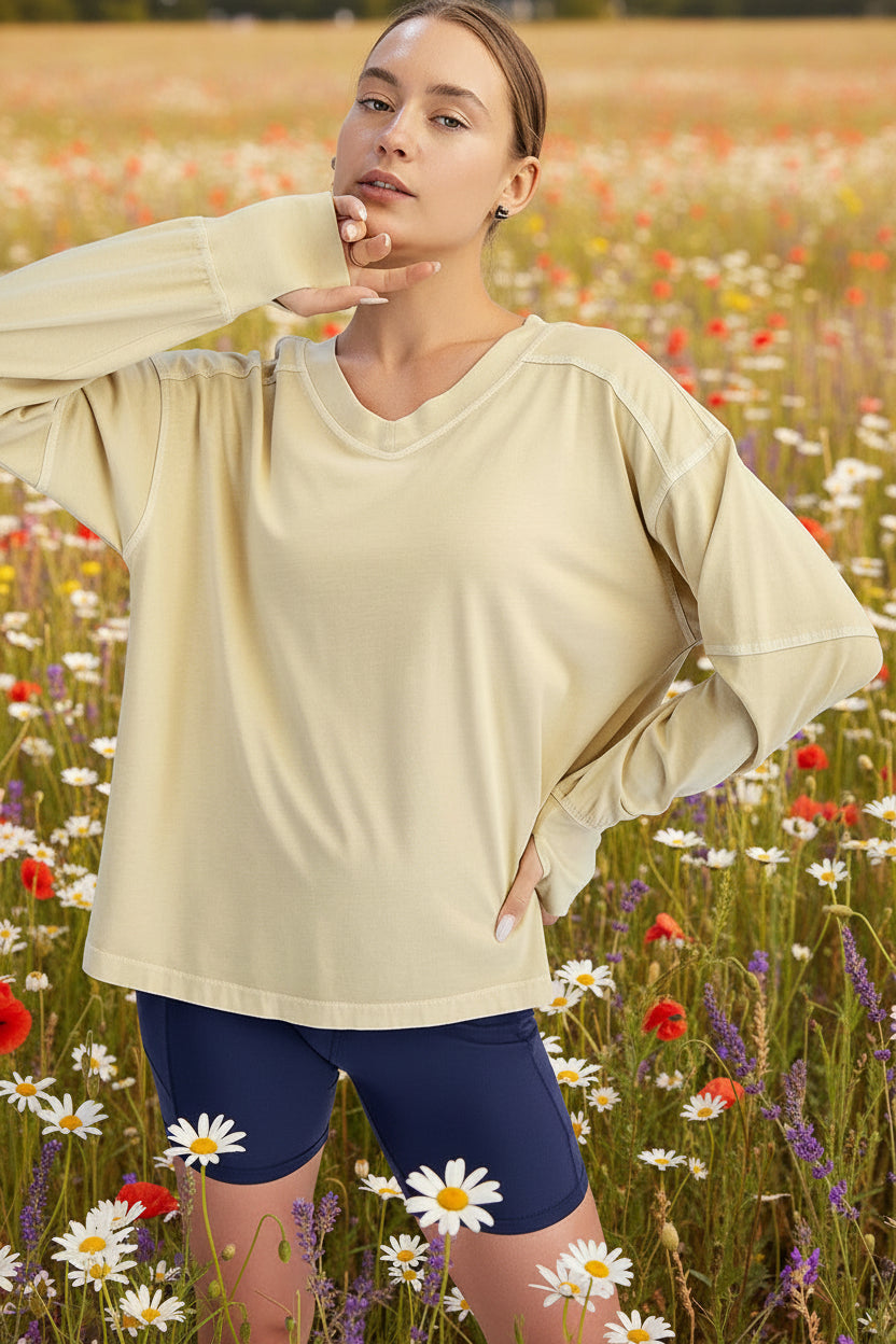 Woman wearing a beige long-sleeve top and navy shorts on a white background