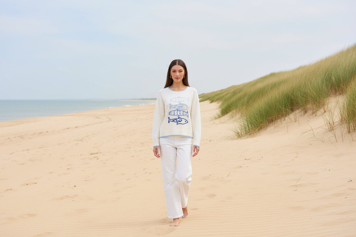 Woman wearing a white sweater with blue fish designs on a beige background