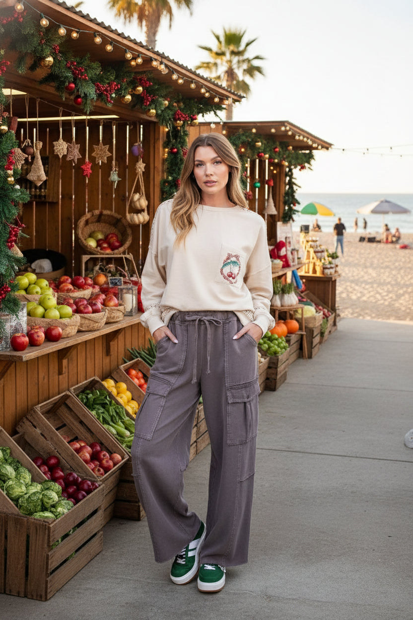 Woman wearing a beige sweater with a colorful design and brown cargo pants on a white background