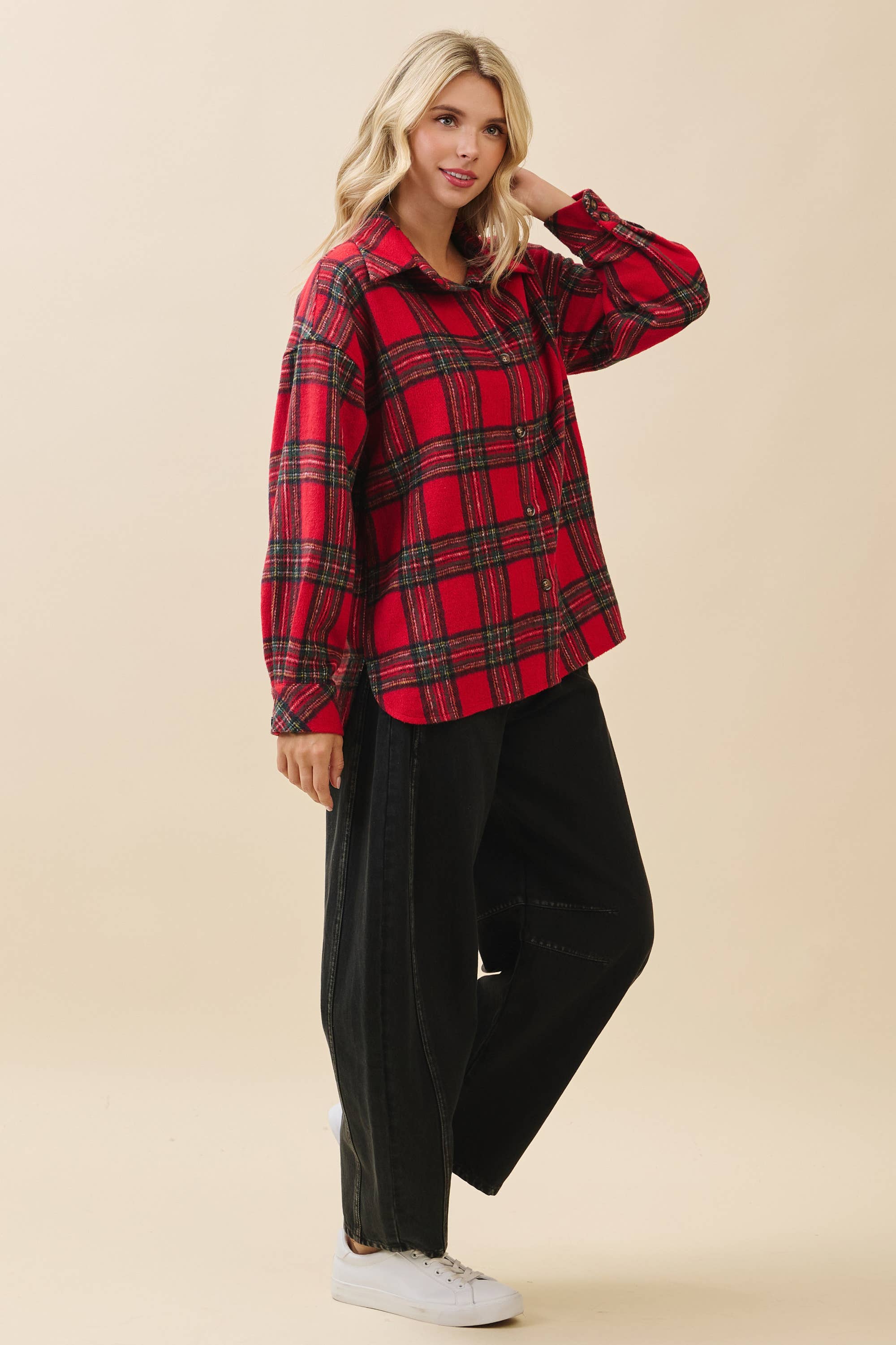 Woman wearing a red plaid shirt and black pants on a beige background