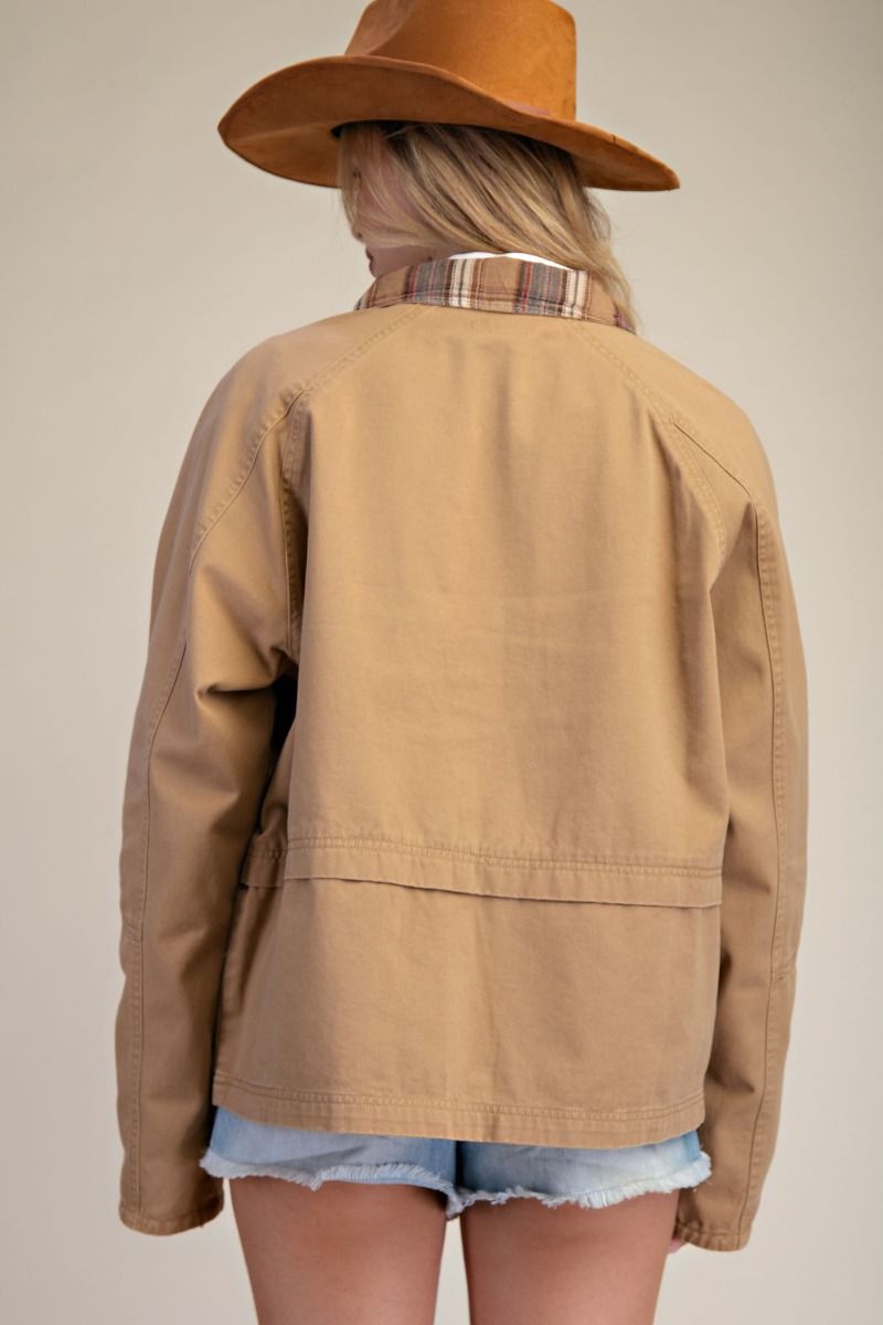 Person wearing a tan jacket and brown hat on a plain background