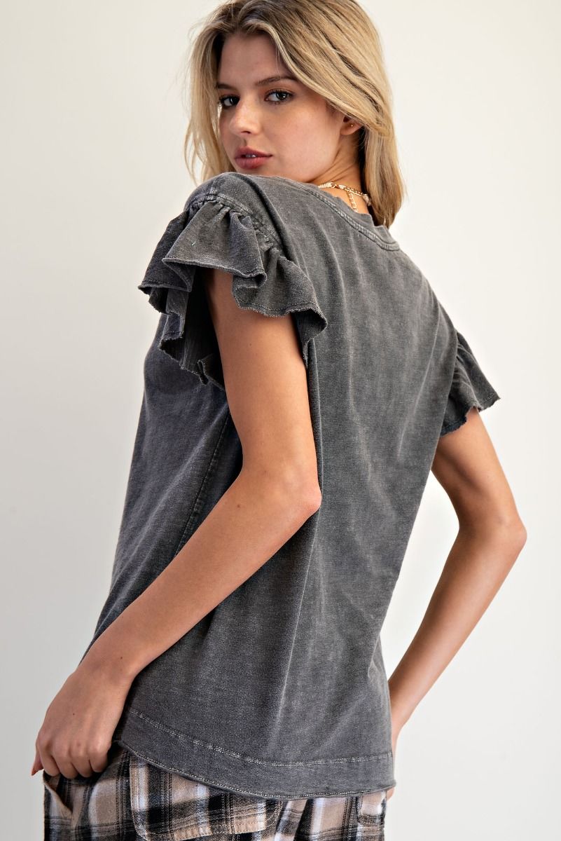 Woman wearing a gray ruffled sleeve top against a plain background