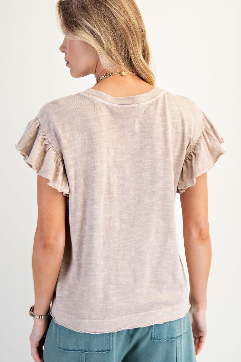 Woman wearing a beige ruffled sleeve top against a white background