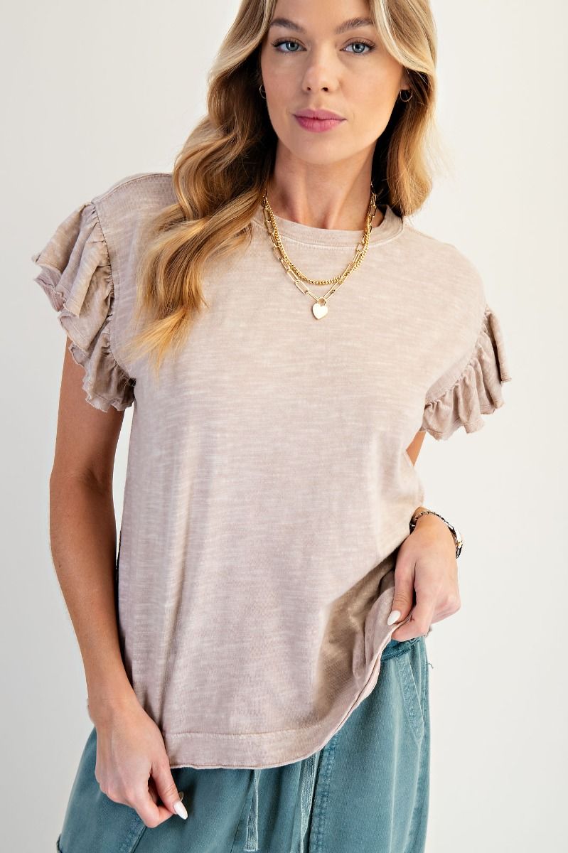 Woman wearing a beige ruffled sleeve top with a plain background