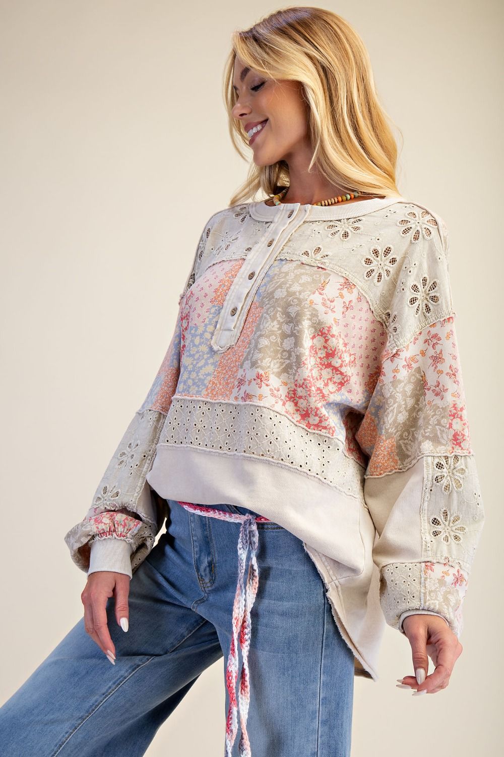Woman wearing a floral patterned sweater and jeans on a plain background