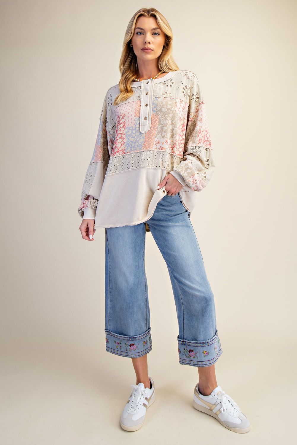 Woman wearing a patterned top and jeans on a beige background