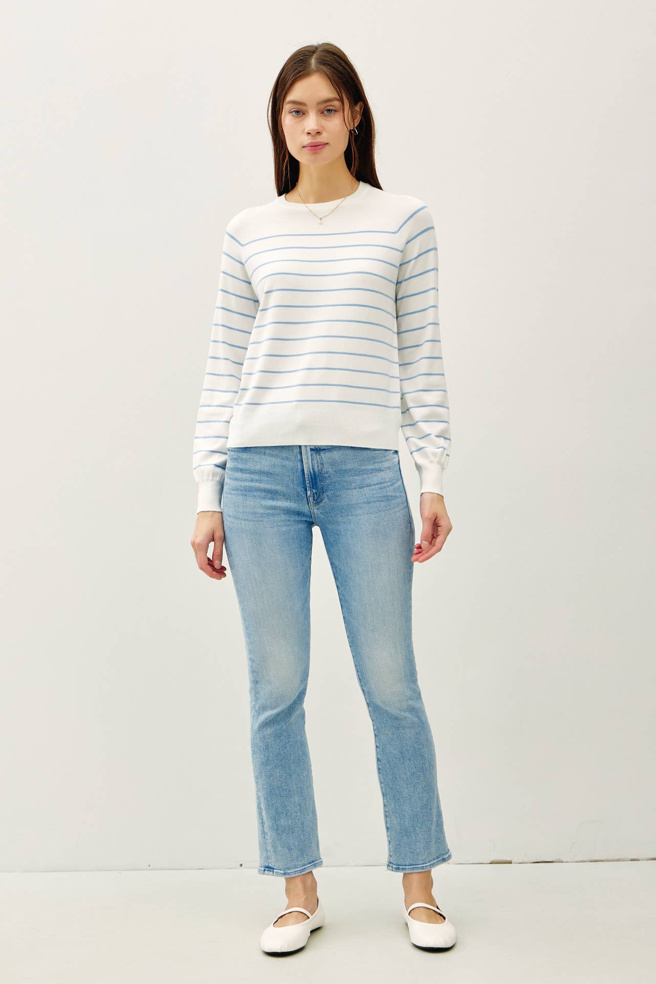 Woman wearing a striped sweater and light blue jeans on a white background