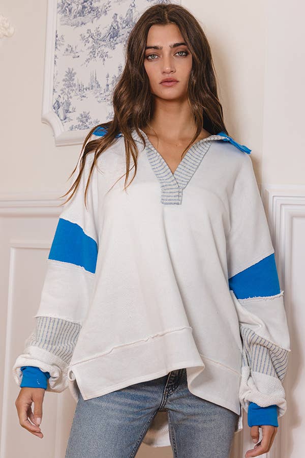 Woman wearing a white sweater with blue accents in a room with decorative elements.