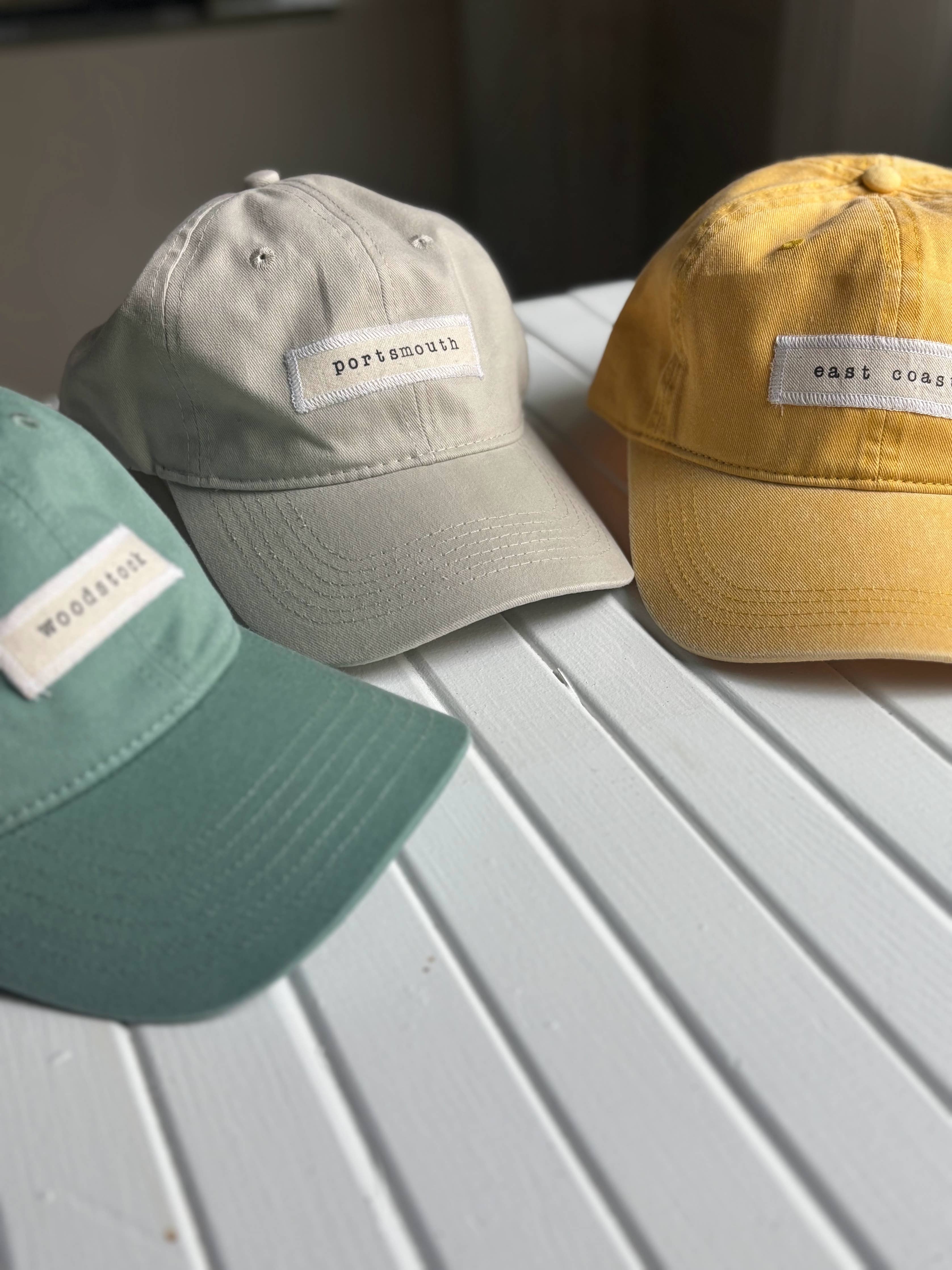 Three baseball caps in different colors with labels on a flat surface