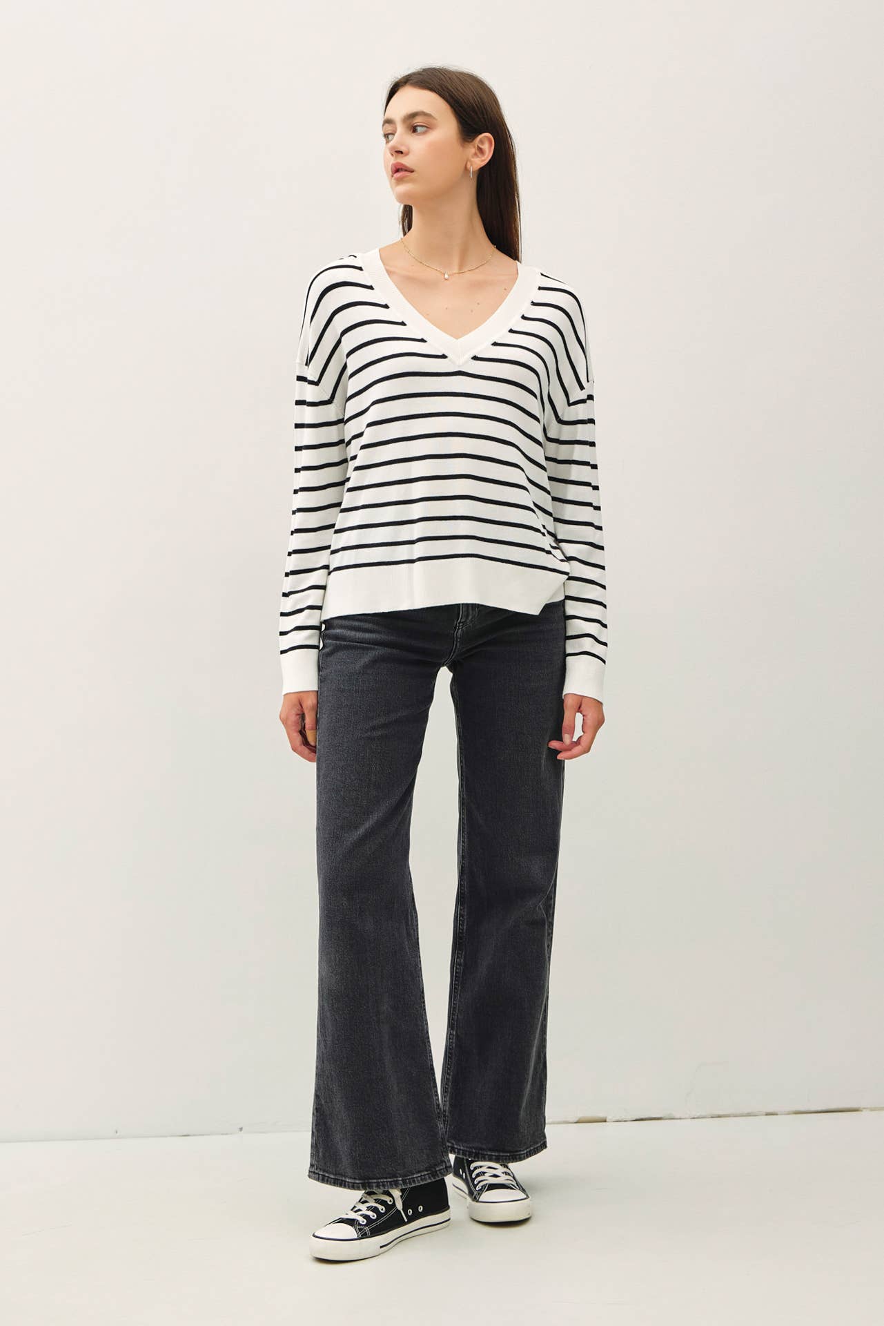 Woman wearing a black and white striped sweater and dark jeans on a white background