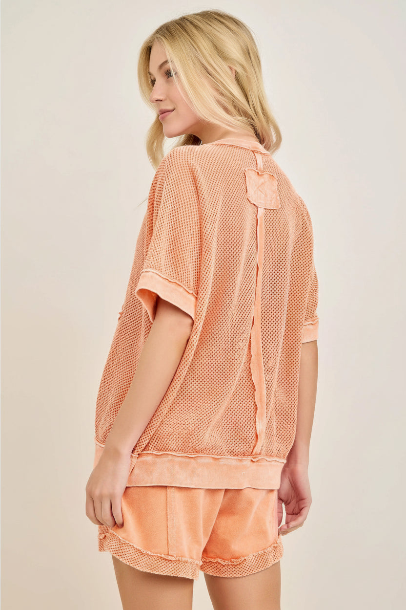 Woman wearing a pink textured shirt and shorts set on a beige background