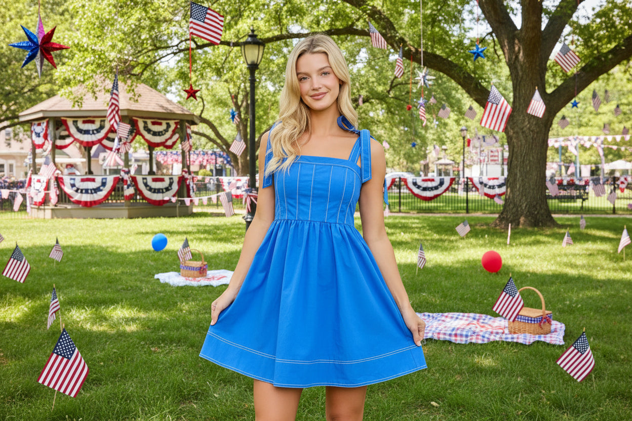 Woman wearing a blue dress with bow straps on a beige background