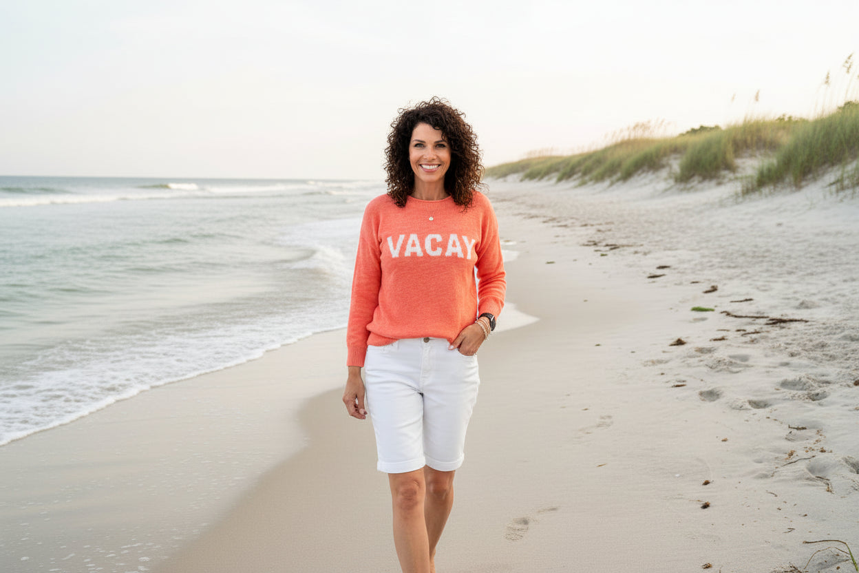 Woman wearing a coral sweater with 'VACAY' text on a white background